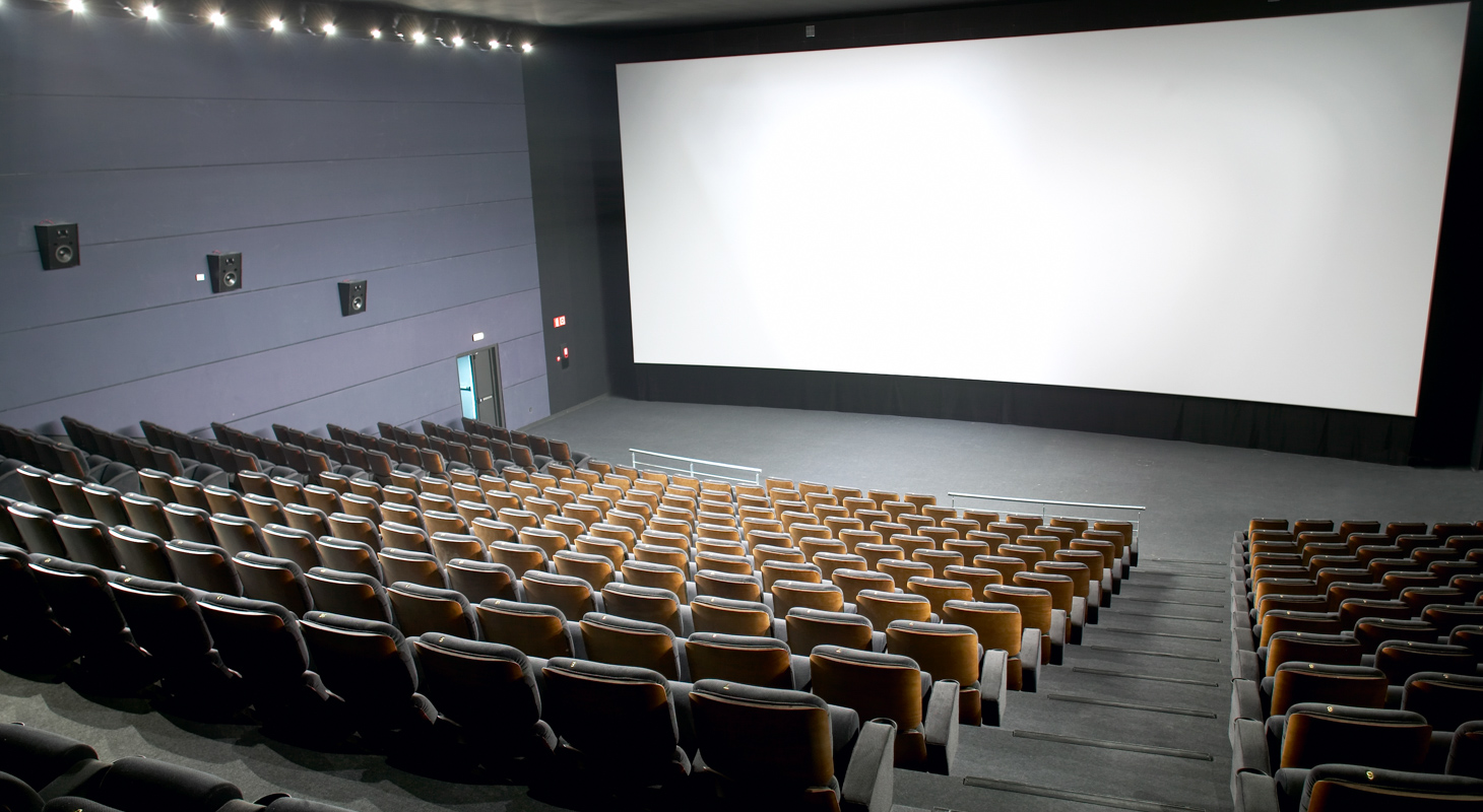 Modern cinema interior with seats and screen.
