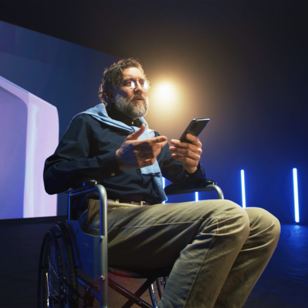 A man in a wheelchair presenting on stage.